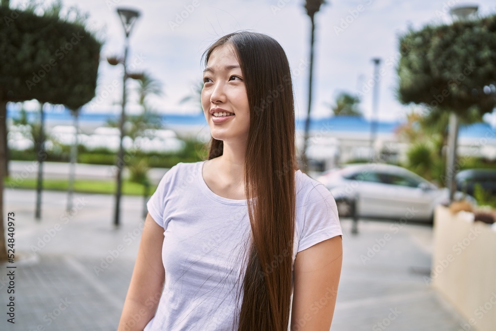 Young chinese girl smiling happy standing at the city.