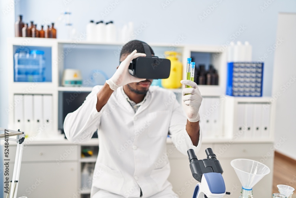 Young african american man wearing scientist uniform using virtual reality glasses at laboratory Young african american man wearing scientist uniform using virtual reality glasses at laboratory