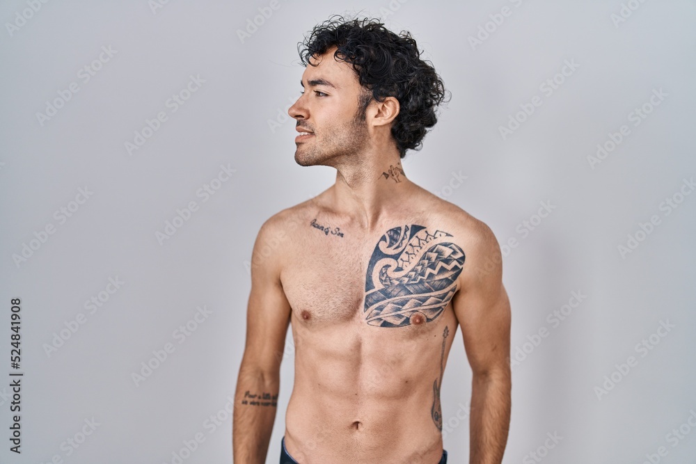 Fototapeta premium Hispanic man standing shirtless looking away to side with smile on face, natural expression. laughing confident.