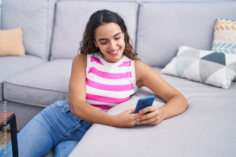 Young beautiful hispanic woman using smartphone sitting on floor at home Young beautiful hispanic woman using smartphone sitting on floor at home