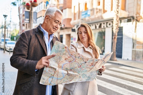 Middle age man and woman couple smiling confident looking city map at street