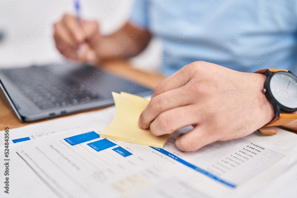 Young latin man business worker writing on reminder paper at office Young latin man business worker writing on reminder paper at office