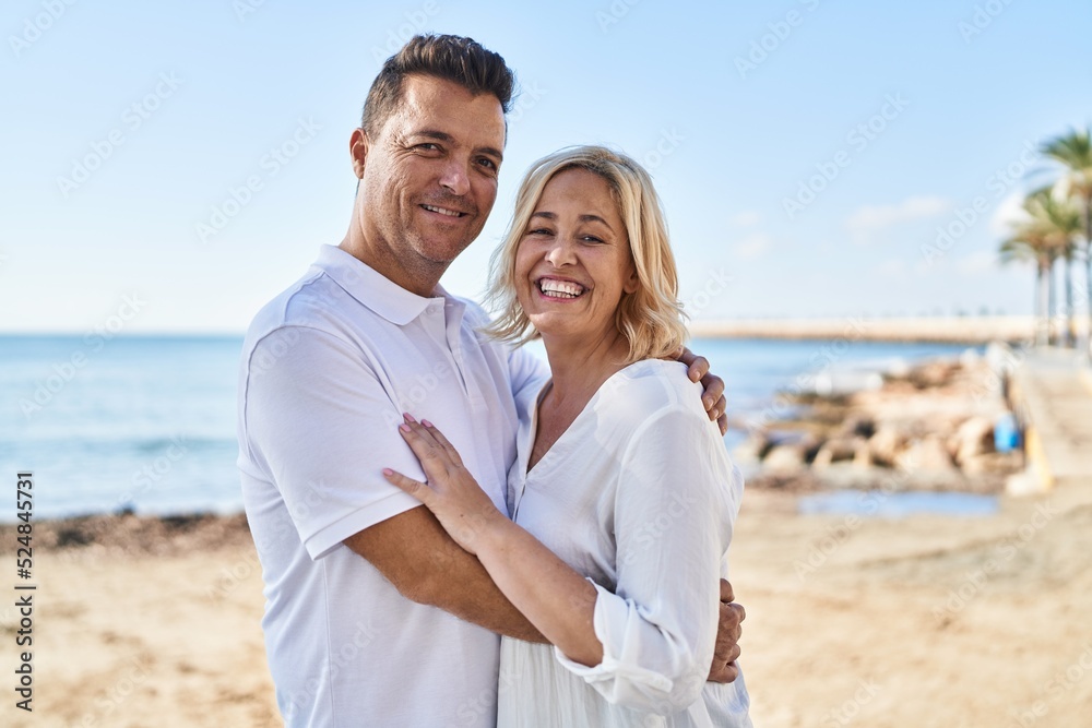 Middle age man and woman couple hugging each other standing at seaside Middle age man and woman couple hugging each other standing at seaside
