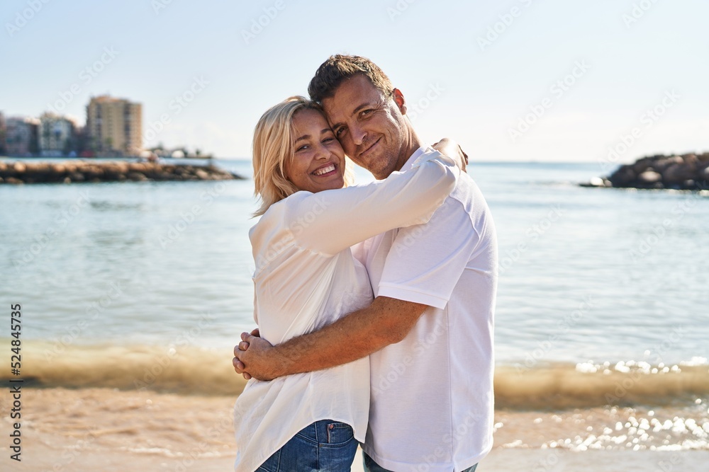 Middle age man and woman couple hugging each other standing at seaside Middle age man and woman couple hugging each other standing at seaside