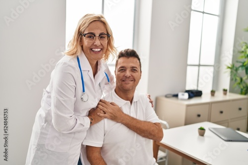 Middle age man and woman doctor and patient hugging each other having medical consultation at clinic