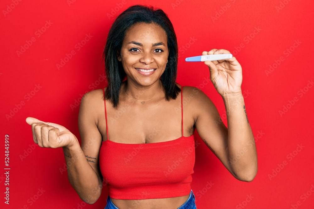 Young african american girl holding pregnancy test result screaming proud, celebrating victory and success very excited with raised arm Young african american girl holding pregnancy test result screaming proud, celebrating victory and success very excited with raised arm