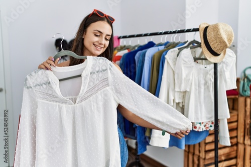 Young caucasian woman holding shirt shopping at clothing store