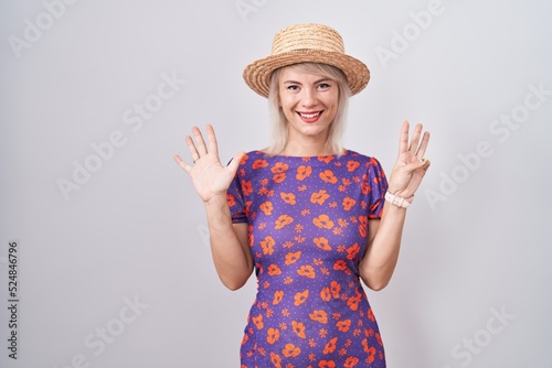 Young caucasian woman wearing flowers dress and summer hat showing and pointing up with fingers number eight while smiling confident and happy.