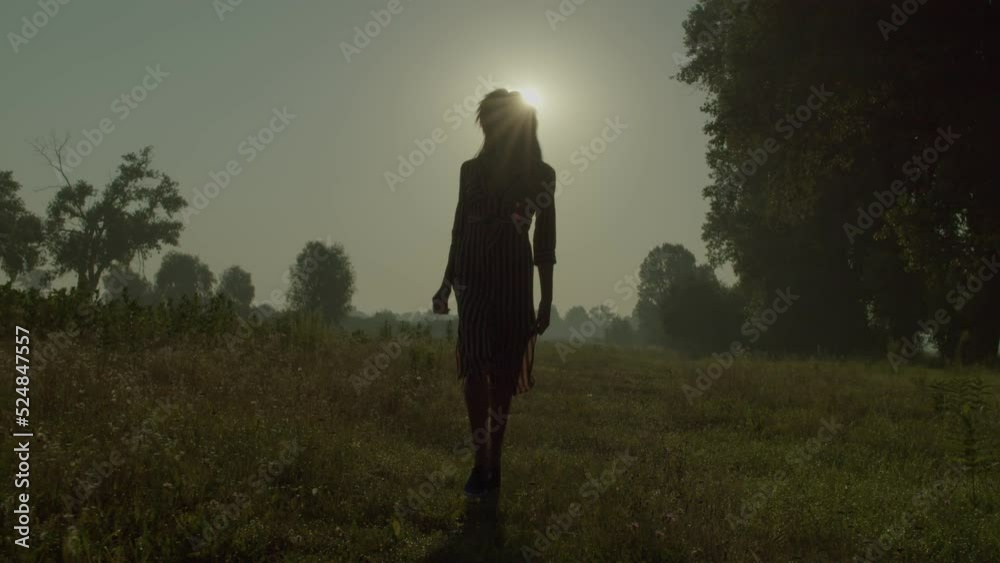 Elegant carefree attractive African woman in summer dress running along grass field, enjoying freedom and summer nature while relaxing in countryside at sunrise. Elegant carefree attractive African woman in summer dress running along grass field, enjoying freedom and summer nature while relaxing in countryside at sunrise.