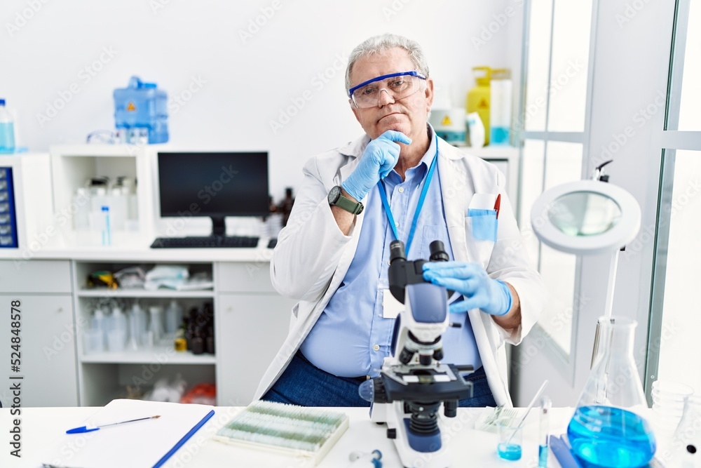 Senior caucasian man working at scientist laboratory with hand on chin thinking about question, pensive expression. smiling and thoughtful face. doubt concept. Senior caucasian man working at scientist laboratory with hand on chin thinking about question, pensive expression. smiling and thoughtful face. doubt concept.