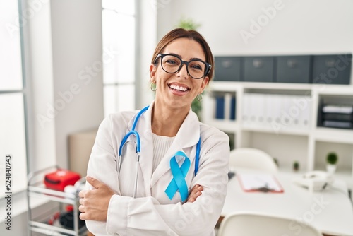 Young brunette doctor woman wearing stethoscope at the clinic happy face smiling with crossed arms looking at the camera. positive person.
