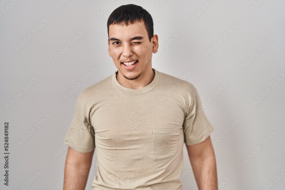 Young arab man wearing casual t shirt winking looking at the camera with sexy expression, cheerful and happy face.