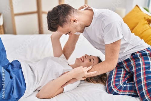 Man and woman couple hugging each other lying on bed at bedroom