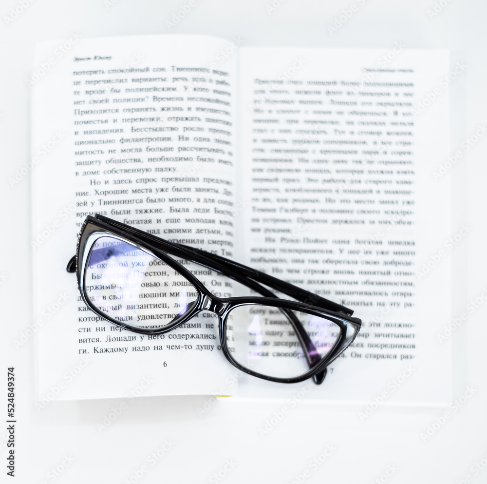 glasses for vision lie next to an open book on a white background glasses for vision lie next to an open book on a white background