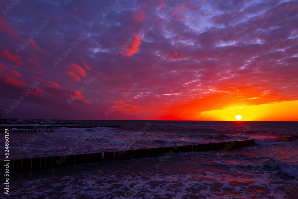 Obraz premium coast of the baltic sea with wooden breakwaters at sunset