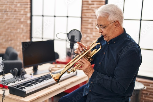 Canvas Print Senior man musician playing trumpet at music studio