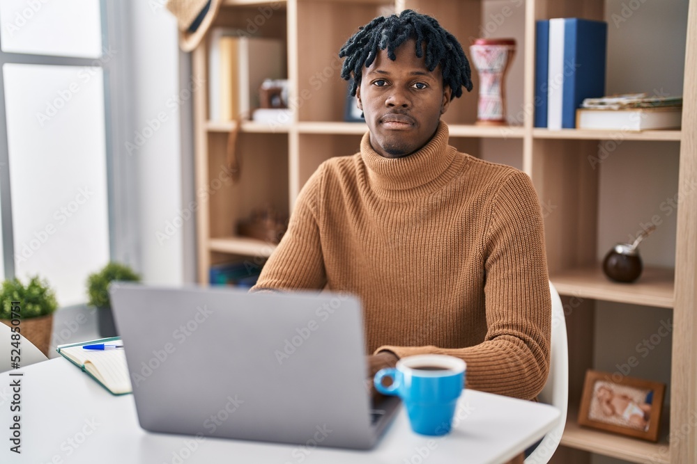 © Krakenimages.com - Young african man with dreadlocks working using computer laptop relaxed with serious expression on face. simple and natural looking at the camera.