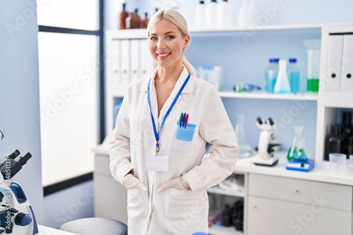 Young blonde woman wearing scientist uniform standing at laboratory