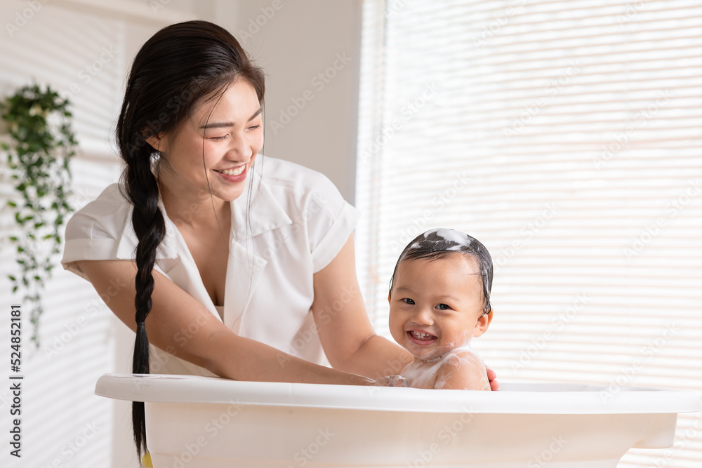 Calm asian baby bathing in bathtub enjoy laughing. mother bathing her son  in warm water.Happy