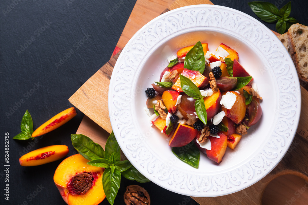 Healthy food concept Tomato Peach Salad with Basil and Goat Cheese on wooden board on black background with copy space