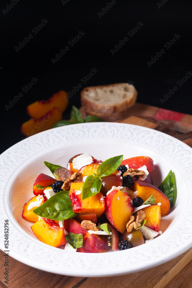 Healthy food concept Tomato Peach Salad with Basil and Goat Cheese on wooden board on black background with copy space