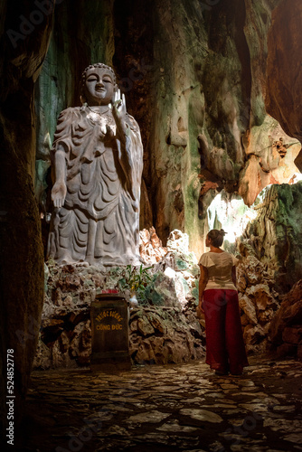 Mujer viajera admirando estatua gigante de Buda en las Marble Mountains, en la ciudad de Da Nang, Vietnam photo