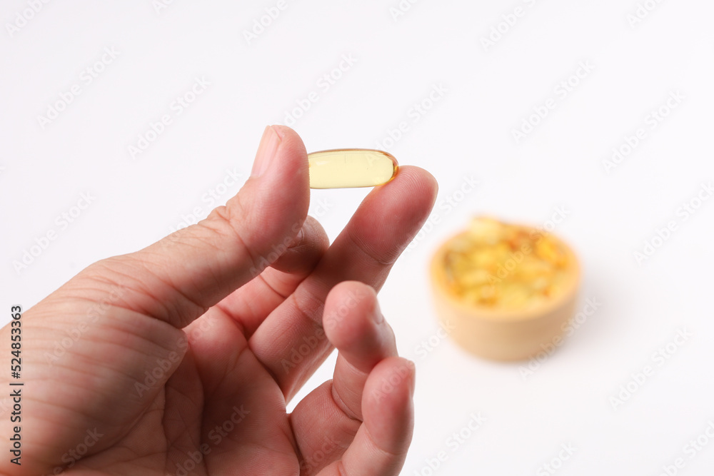 Hand hold fish oil capsules fish with omega 3 and vitamin D and supplements concept on white background Hand hold fish oil capsules fish with omega 3 and vitamin D and supplements concept on white background