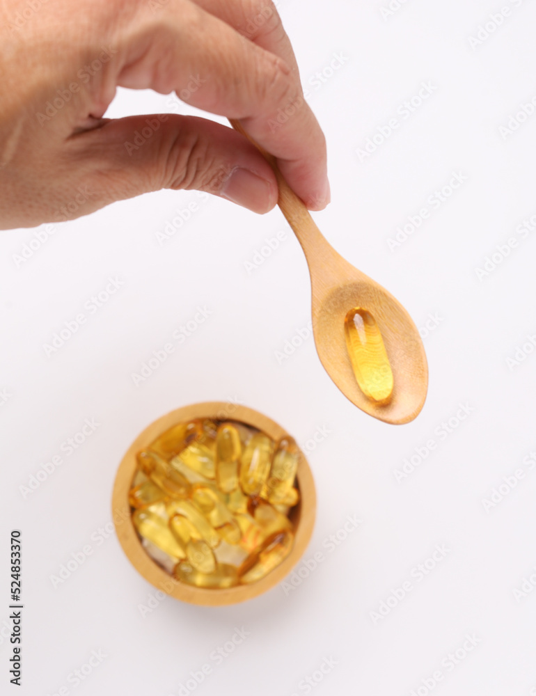 Hand hold fish oil capsules fish with omega 3 and vitamin D and supplements concept on white background Hand hold fish oil capsules fish with omega 3 and vitamin D and supplements concept on white background