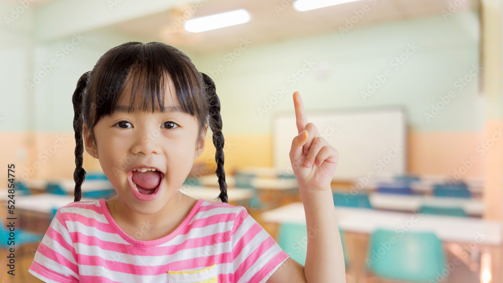 asian child point upper with blurred classroom background asian child point upper with blurred classroom background