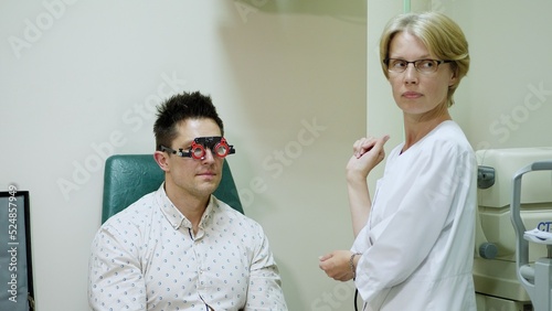 female doctor ophthalmologist is checking the eye vision of handsome young man in modern clinic. Doctor and patient in ophthalmology clinic. Doctor is giving advices. High quality photo photo