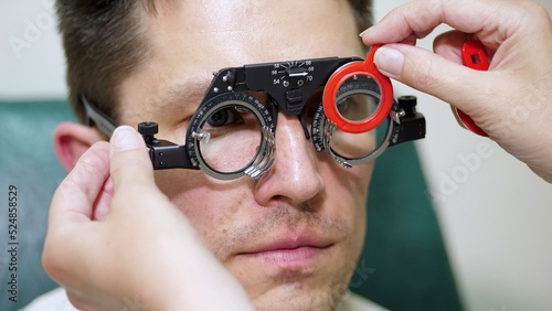 face close-up , ophthalmologist examining patient man with optometrist trial frame, visual inspection device. male patient to check vision in ophthalmological clinic,. High quality photo