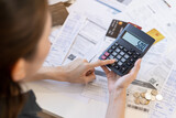 Close up hand of stress asian young businesswoman using calculator for calculate tax, expense of bills, credit card for payment on due deadline on table at home. Financial, finance people concept.
