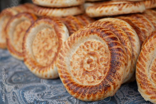 Typical traditional flatbread with crunchy crust with sesam just baked in tandoor on market display of old bakery. Fresh yummy flavored bread from clay tandoor for sale. Tandoor tortillas