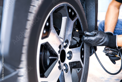 Auto mechanic checking air pressure and inflating car tires. Concept of car care service and maintenance or fix the car leaky or flat tire.