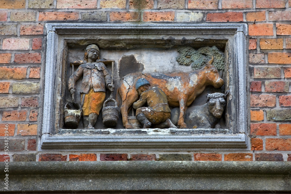 Fototapeta premium A wall bas relief in Huidenvettersplein (Tanners Square), representing dairy production, in the historic centre of Bruges, Unesco World Heritage Site, Belgium, Europe