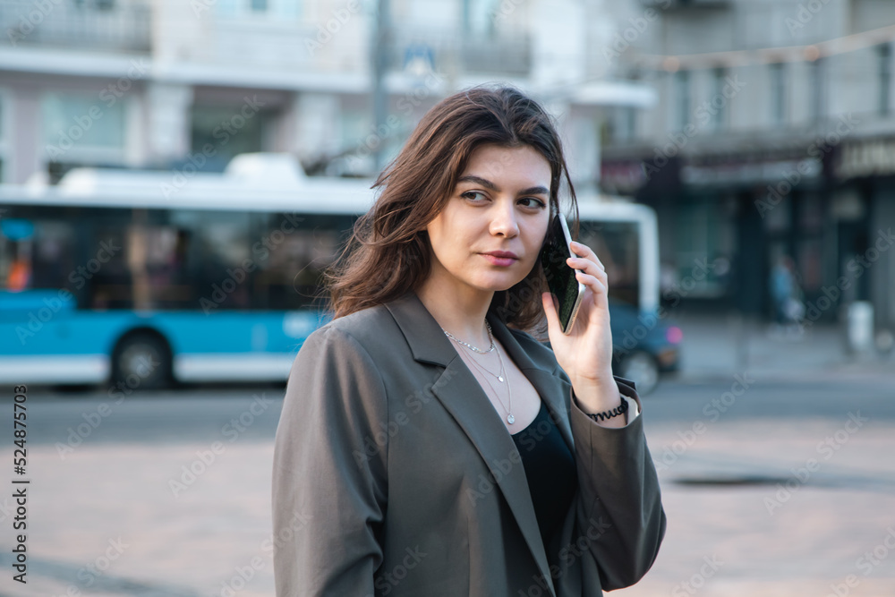 Business young woman with a smartphone on a blurred background of the city.