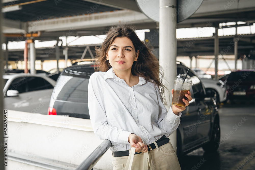 Attractive business young woman in a car park with a cup of coffee. Attractive business young woman in a car park with a cup of coffee.