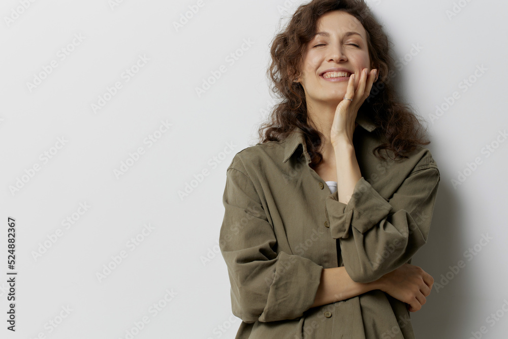 Smiling happy curly beautiful woman in casual khaki green shirt recline on hand closing eyes enjoy cool day posing isolated on over white background. People Emotions Lifestyle concept. Copy space Smiling happy curly beautiful woman in casual khaki green shirt recline on hand closing eyes enjoy cool day posing isolated on over white background. People Emotions Lifestyle concept. Copy space