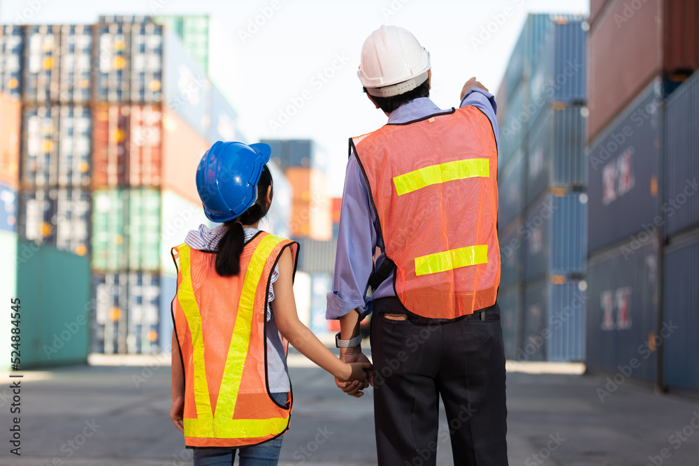 back view engineer or factory worker with her daughter looking forward and pointing up to something in containers warehouse storage back view engineer or factory worker with her daughter looking forward and pointing up to something in containers warehouse storage