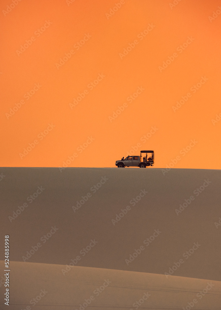 Fototapeta premium silhouette of an offroad car in the desert at sunset