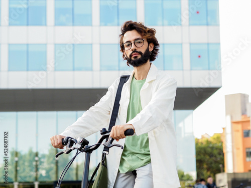 Young digital entrepreneur man with a bike in a financial district looking at camera.Sustainable mobility, new digital business