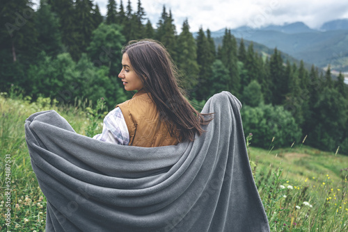 Foto A young woman wrapped in a blanket in the mountains.
