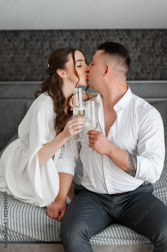 Brides Couple Kissing Holding Glasses With Drink Sitting In Apartment Brides Couple Kissing Holding Glasses With Drink Sitting In Apartment