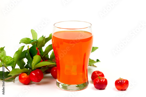 Acerola or barbados cherry juice in glass with fresh acerola cherry fruits isolated on white background.