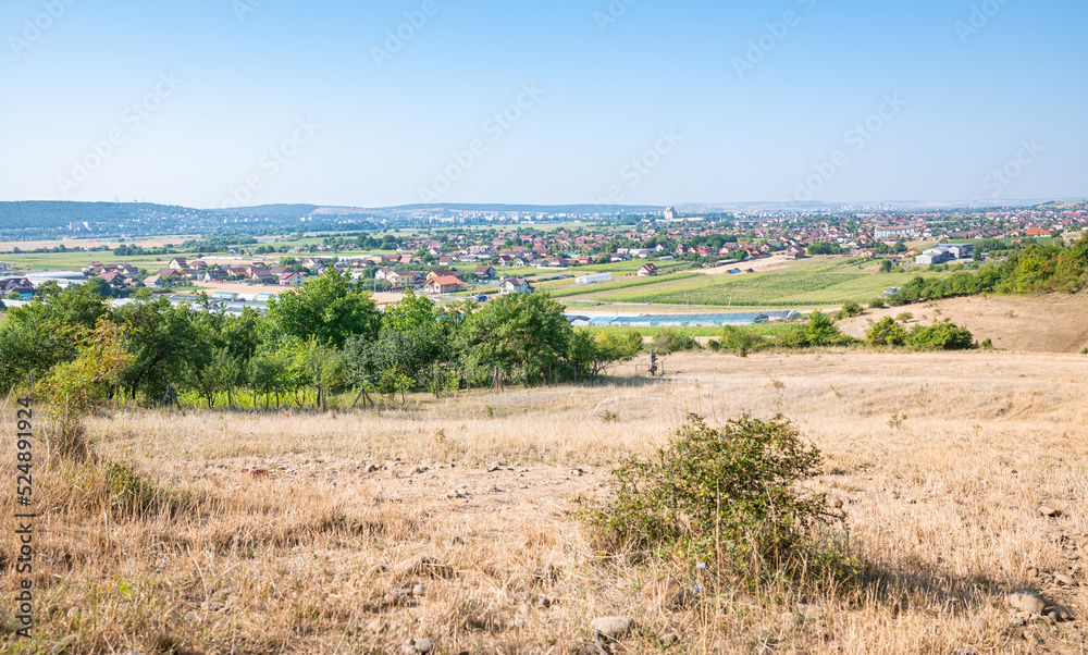 View from a hill over the valley of the river Mureș with the village of Sântana de Mureș and the city of Targu Mureș, Romania in the background.