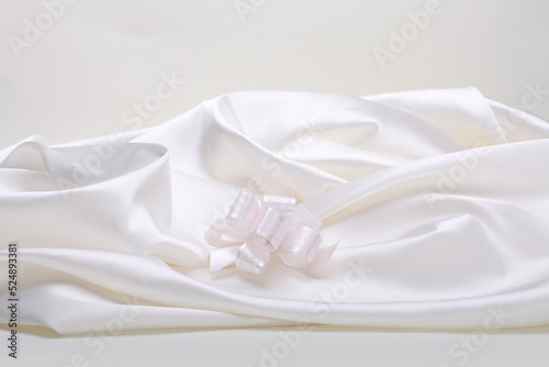 White beige pearl wave fabric silk and bow. Abstract texture horizontal copy space background.