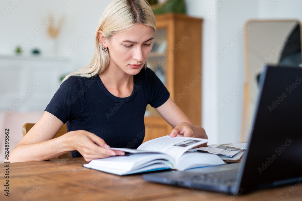 Woman student reading book sitting at table