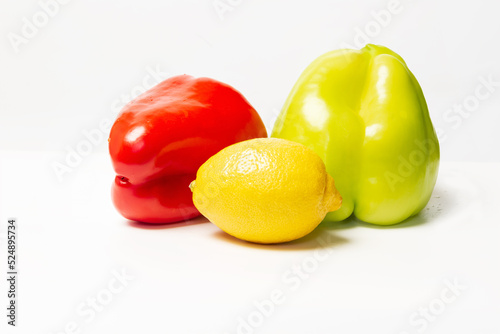 Two sweet peppers and lemon isolated on white