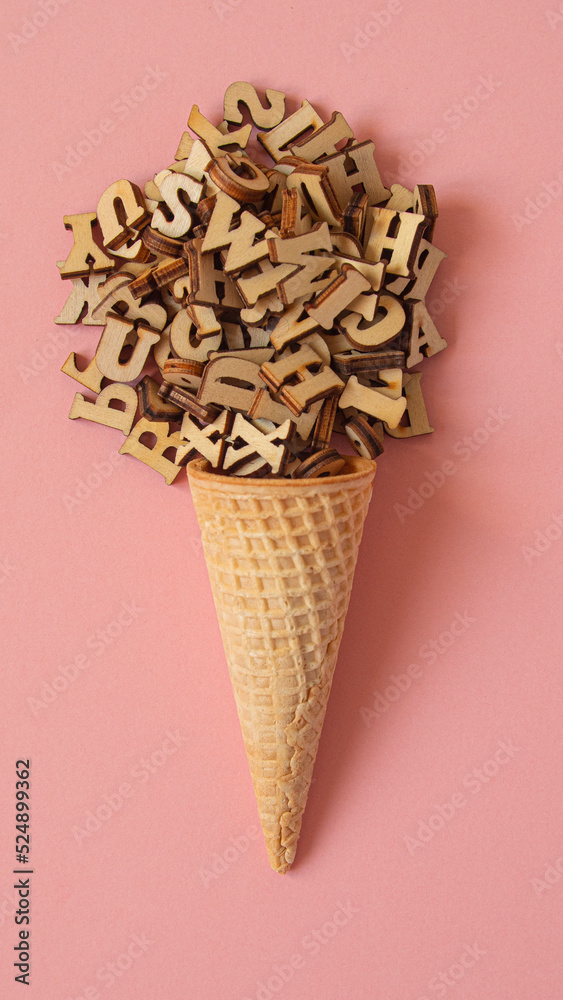 Cone ice cream formed with a ball of wooden letters on a pink background