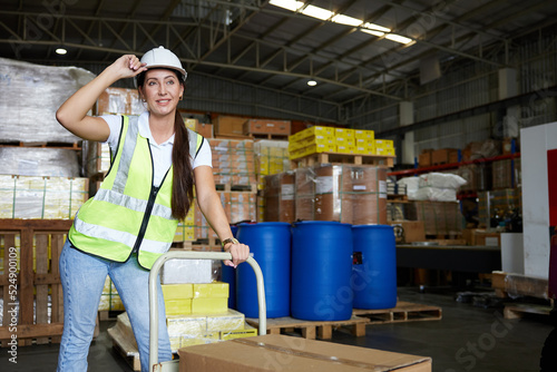 female factory worker pushing cart with corrugated box in the warehouse storage